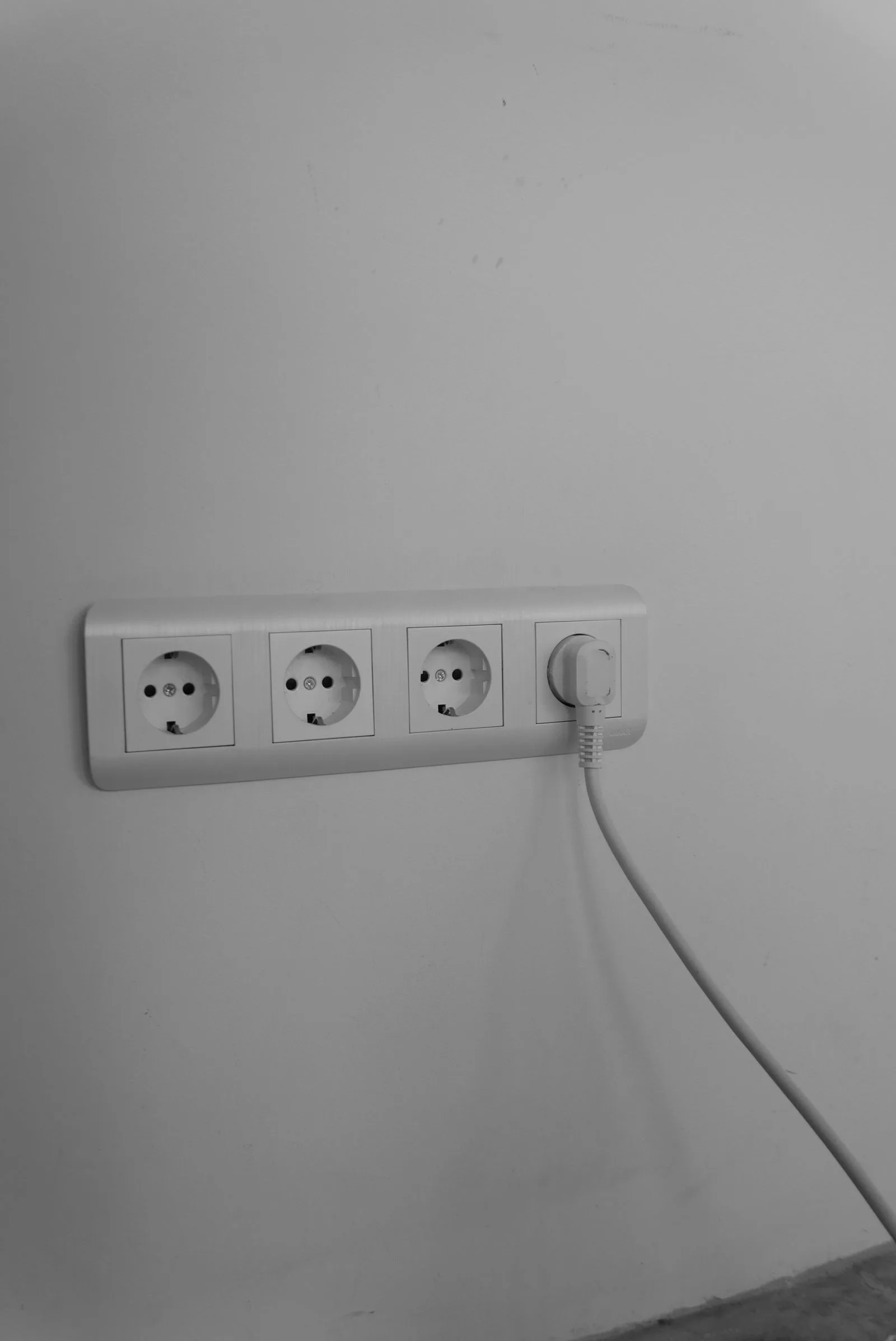 Nahaufnahme mehrerer neu gesetzter, moderner Steckdosen an einer weißen Wand